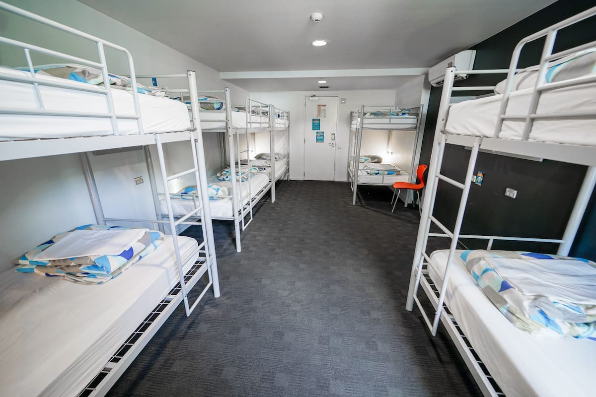 A room with bunk beds, a desk, and a chair.