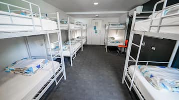 A room with bunk beds, a desk, and a chair.