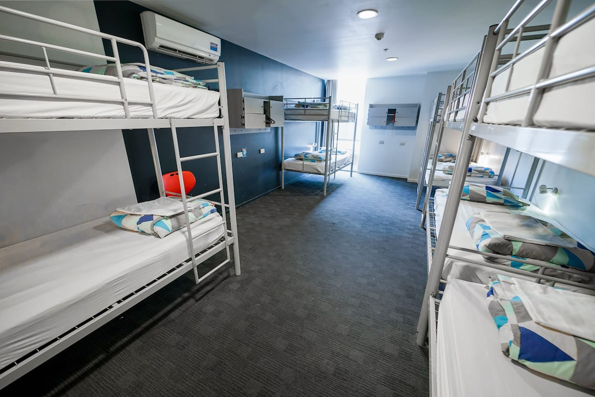 A bunk room with bunk beds, a small kitchenette, and a window.