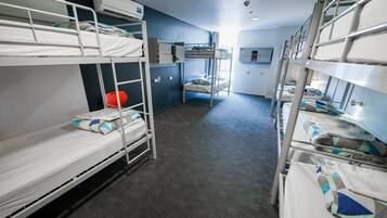 A bunk room with bunk beds, a small kitchenette, and a window.