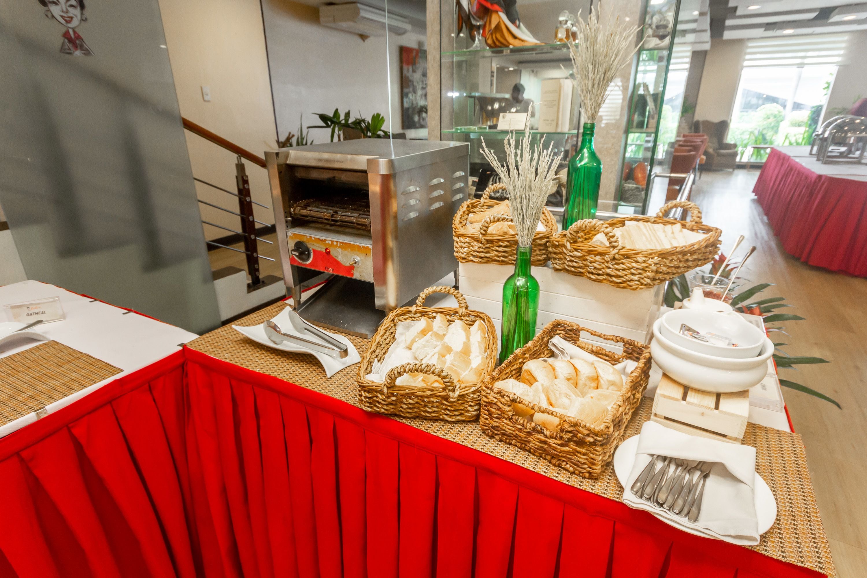 A buffet setup with baskets of bread, a green bottle, and a white bowl on a table.