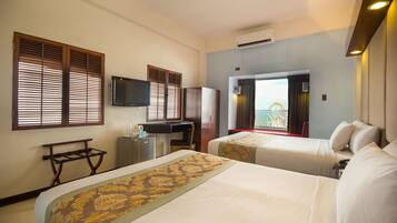 A hotel room with two beds, a desk, a television, and a window with blinds.