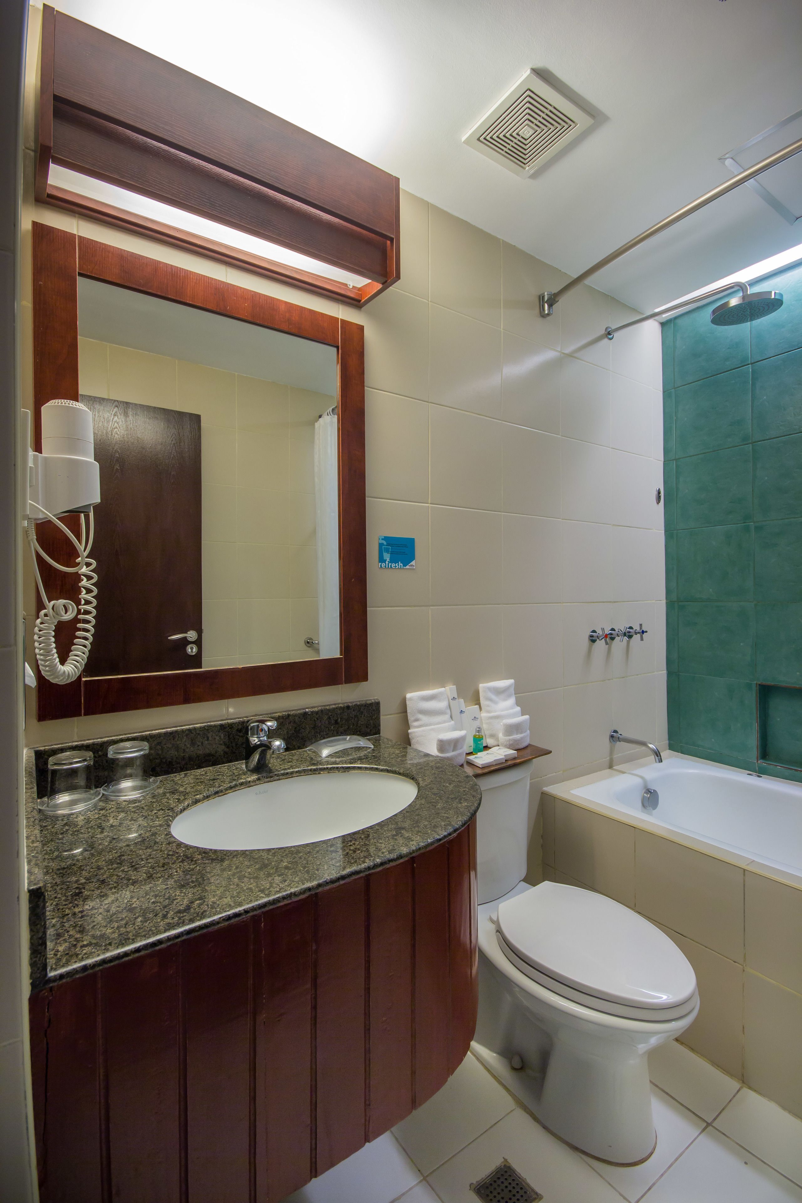 A bathroom with a sink, mirror, toilet, and shower.