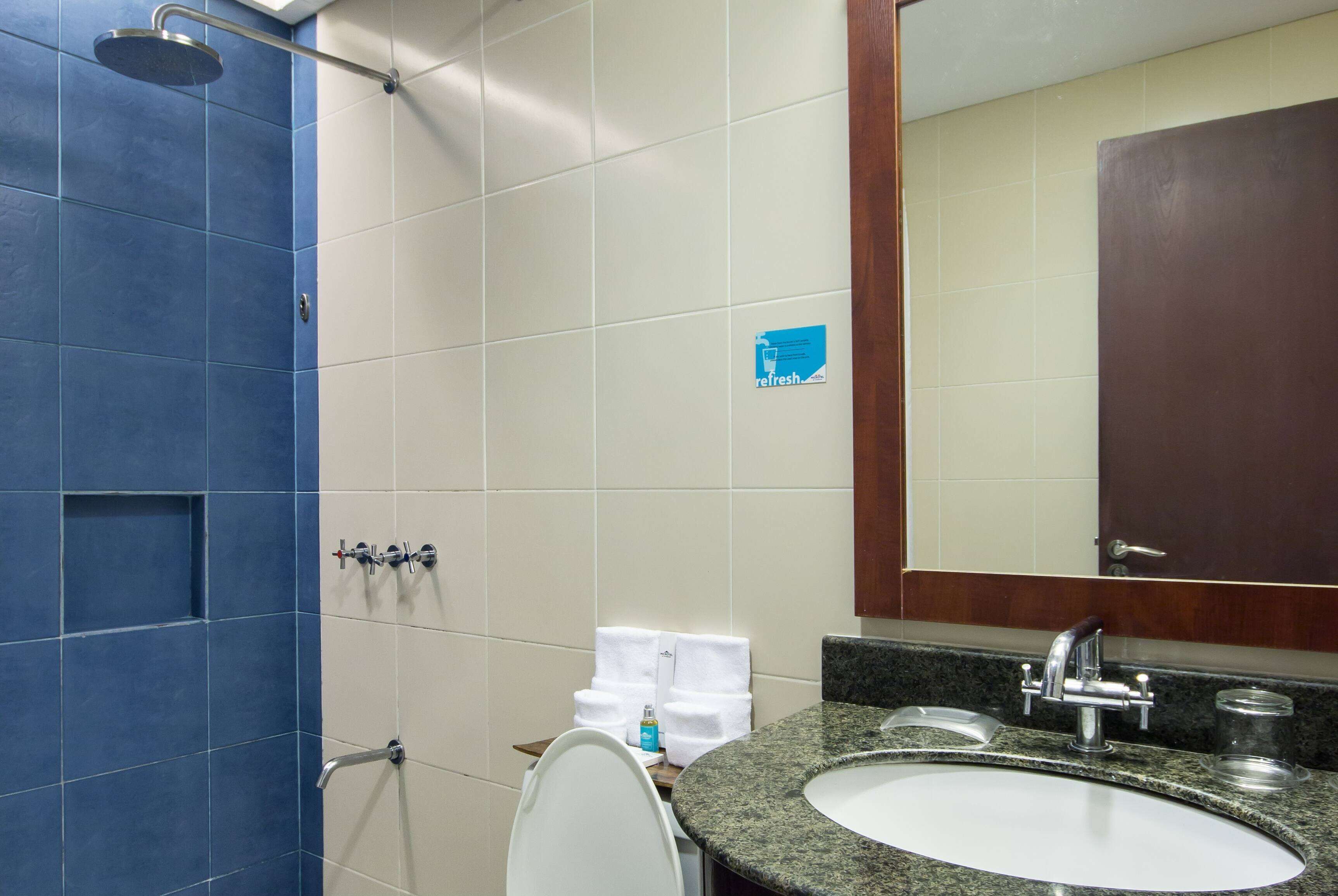 A bathroom with a shower, a sink, and a mirror.