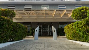 A multi-story hotel with a modern design, featuring a prominent entrance with a canopy and a large logo at the top.
