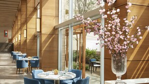 A modern restaurant with blue chairs and round tables, large windows, and a wooden interior. - Taj City Centre New Town Kolkata (Barasat)