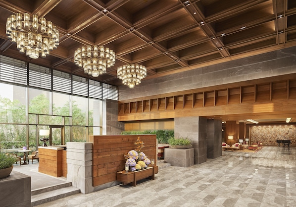 A spacious lobby with a wooden reception desk, large windows, and a seating area with a piano.