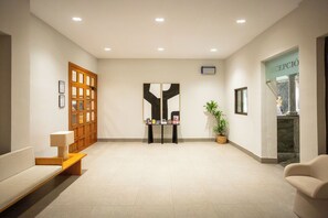 A reception area with a wooden door, a reception desk, a potted plant, and a reception desk with framed certificates.