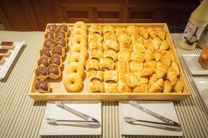 A tray of assorted pastries including muffins, donuts, and croissants.