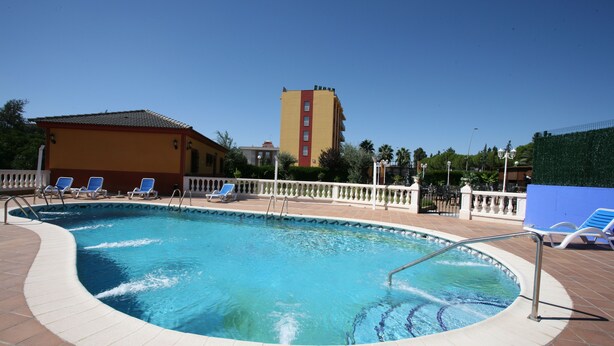 A swimming pool with a tiled deck, surrounded by lounge chairs and a white fence. - Hotel Zeus (Merida)