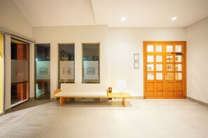 A reception area with a wooden bench, a wooden door with glass panels, and framed certificates on the wall.