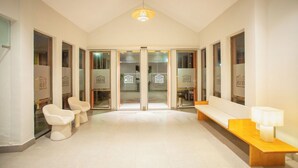 A hotel lobby with a reception desk, seating area, and glass doors leading to other rooms. - Hotel Zeus (Merida)