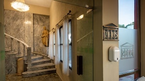 A marble staircase with a statue, a hand sanitizer dispenser, and a hotel sign. - Hotel Zeus (Merida)