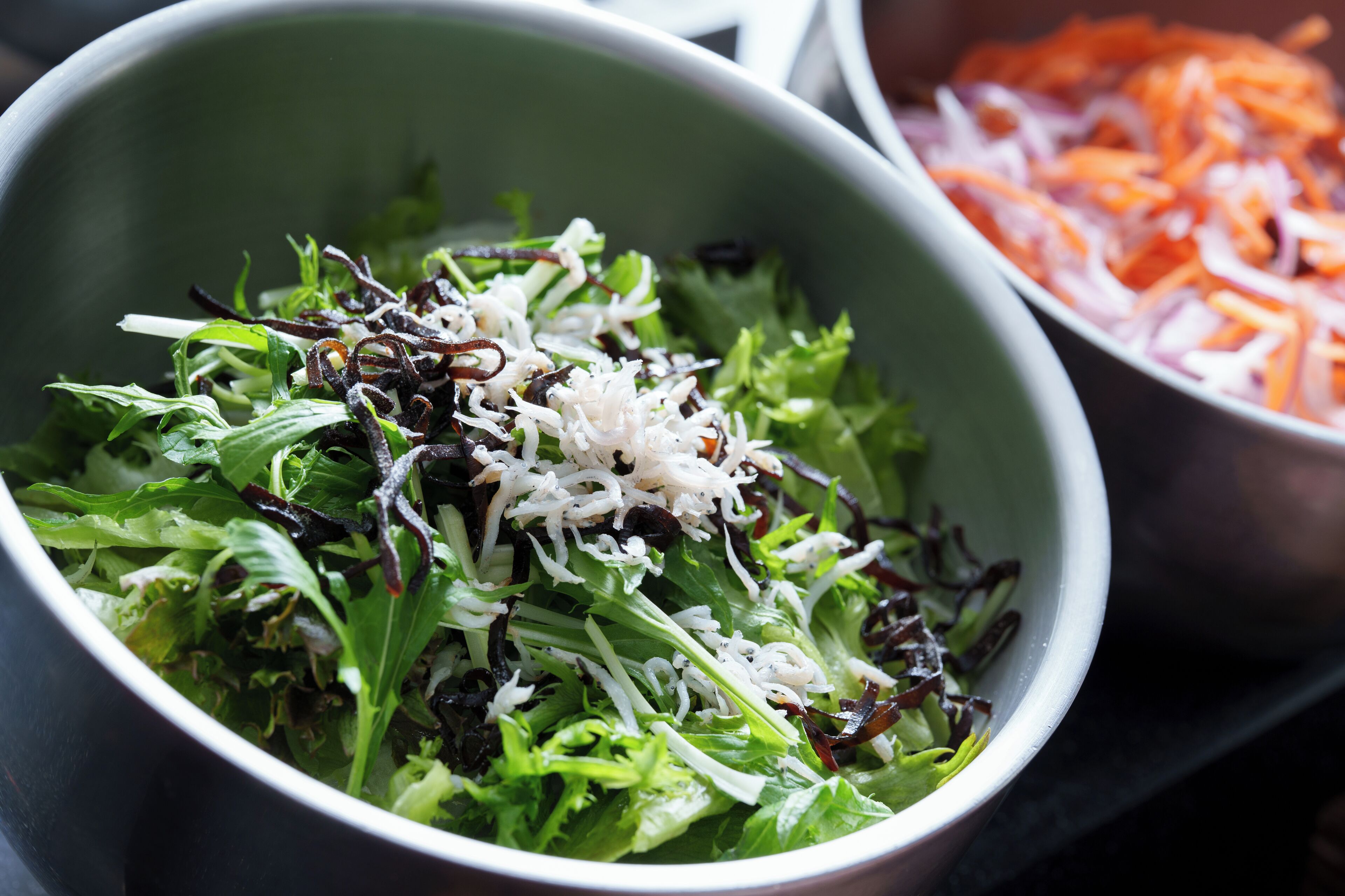 A bowl of salad with mixed greens and shredded cheese.