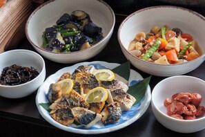 A table with various dishes, including fish, vegetables, and possibly some pickled items. - Hotel Vista Ebina (Ebina)
