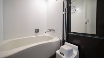 A modern bathroom with a white bathtub, a glass shower enclosure, and a white trash bin.