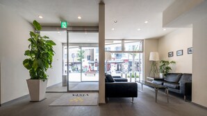 A hotel lobby with a reception desk, seating area, and a large potted plant.