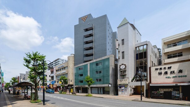 A multi-story building with a modern architectural design, featuring a prominent logo on the top.