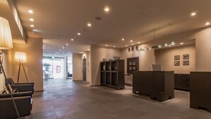 A modern lobby with a reception desk, seating area, and a wall with framed pictures.