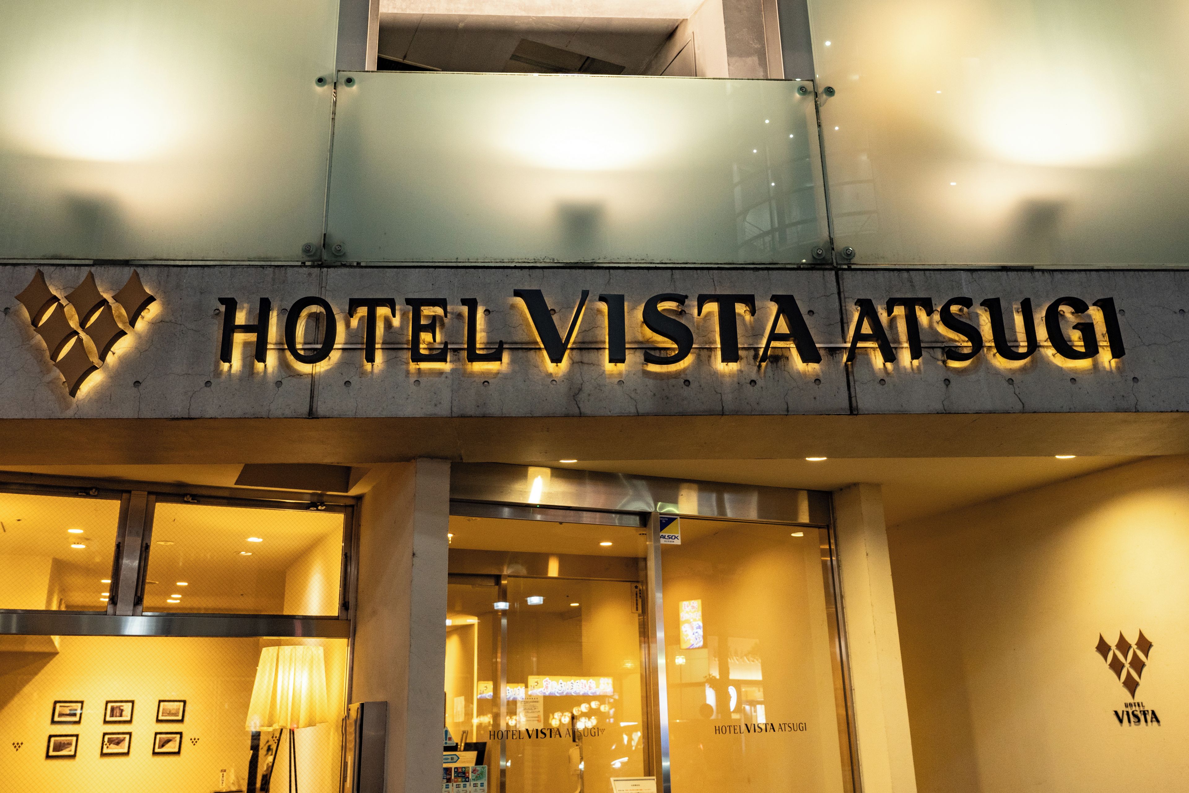 The exterior of Hotel Vista Atsugi with a prominent sign and a logo.