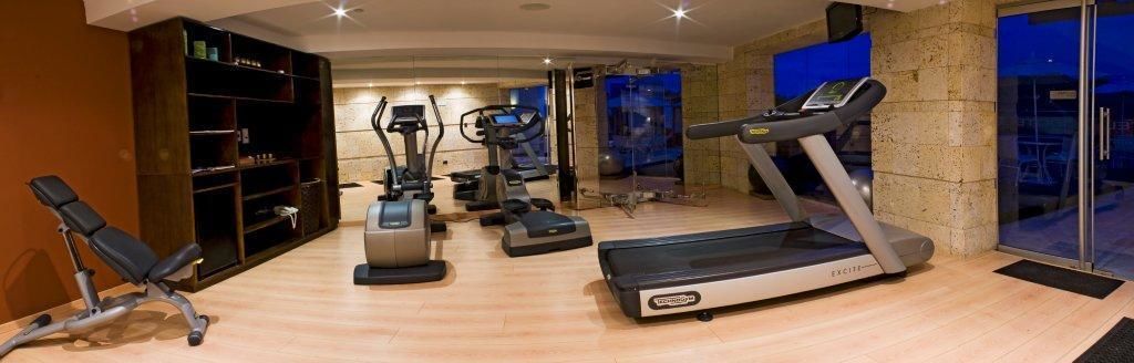 Un gimnasio con cintas de correr, elípticas y una bicicleta estática.