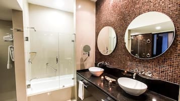 A modern bathroom with a glass-enclosed shower, two sinks, and a large mirror.