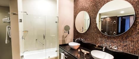 Un bagno moderno con cabina doccia in vetro, due lavandini e uno specchio grande.