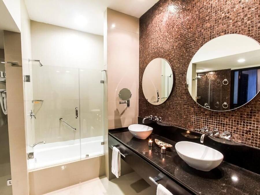 A modern bathroom with a glass-enclosed shower, two sinks, and a large mirror.