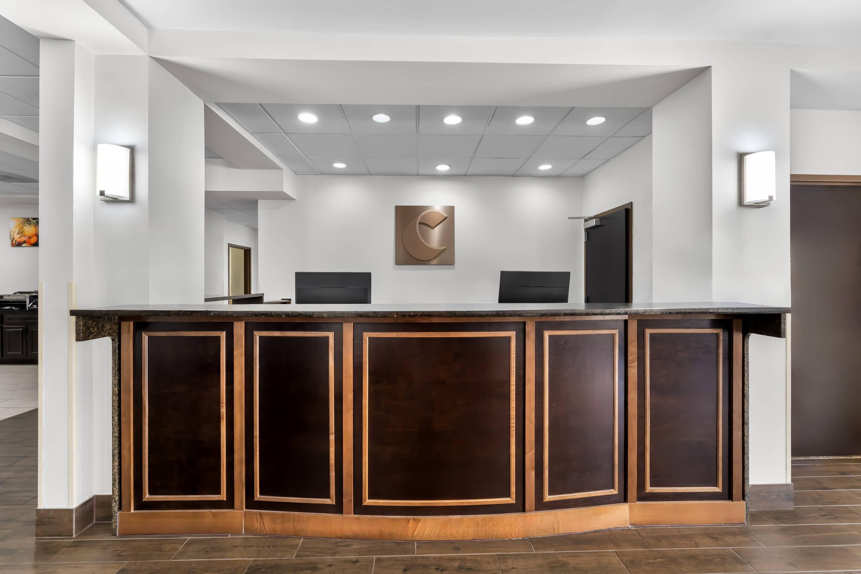 Un comptoir d’accueil au design moderne, agrémenté d’une œuvre d’art centrale, de plusieurs postes informatiques et d’un intérieur épuré aux couleurs claires.