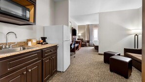 A compact hotel room with a kitchenette, a flat-screen TV, a sofa, and a lamp. - Comfort Inn & Suites Augusta West Near Fort Gordon (Augusta)