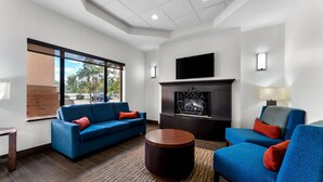 A modern living room with a blue sofa, a round wooden coffee table, and a fireplace. - Comfort Inn & Suites Augusta West Near Fort Gordon (Augusta)