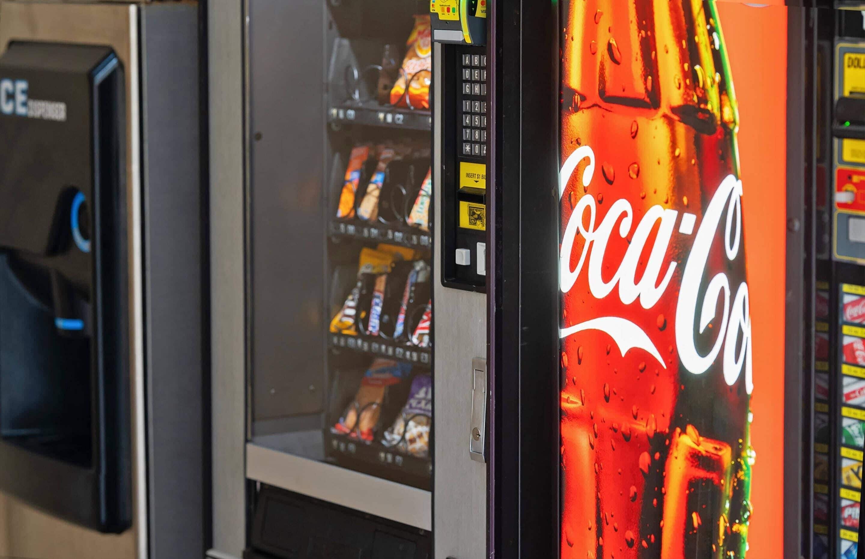 Un distributeur automatique orné du logo Coca-Cola et doté d’un terminal de paiement numérique.