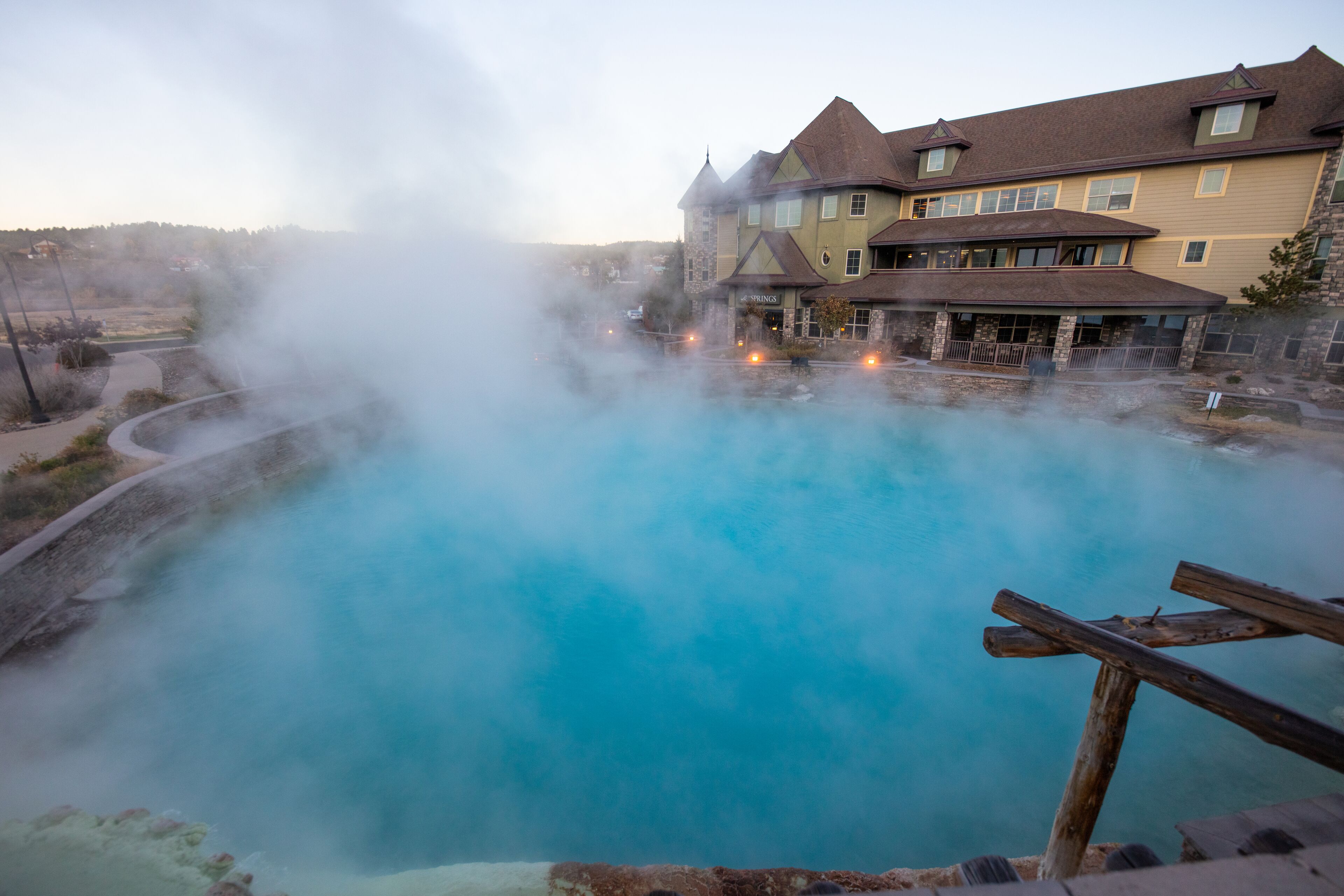 Un edificio grande con una piscina rodeada de vapor, indicando un centro de spa o aguas termales.