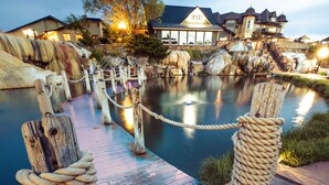 A wooden dock with rope moorings leading to a calm water body, surrounded by buildings with illuminated windows. - The Springs Resort & Spa (Pagosa Springs)