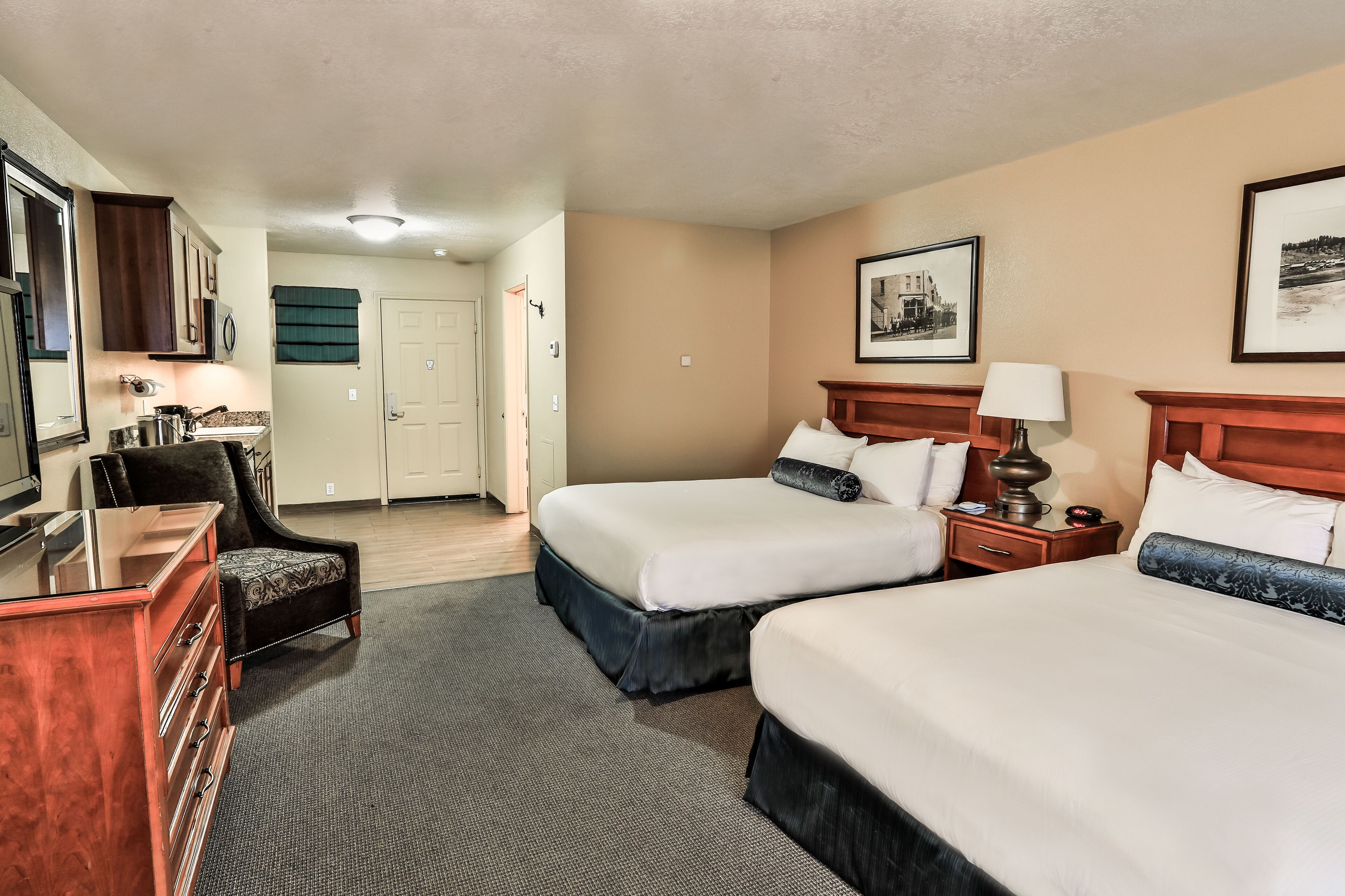 Une chambre d’hôtel avec deux lits, un bureau, une chaise et une commode.