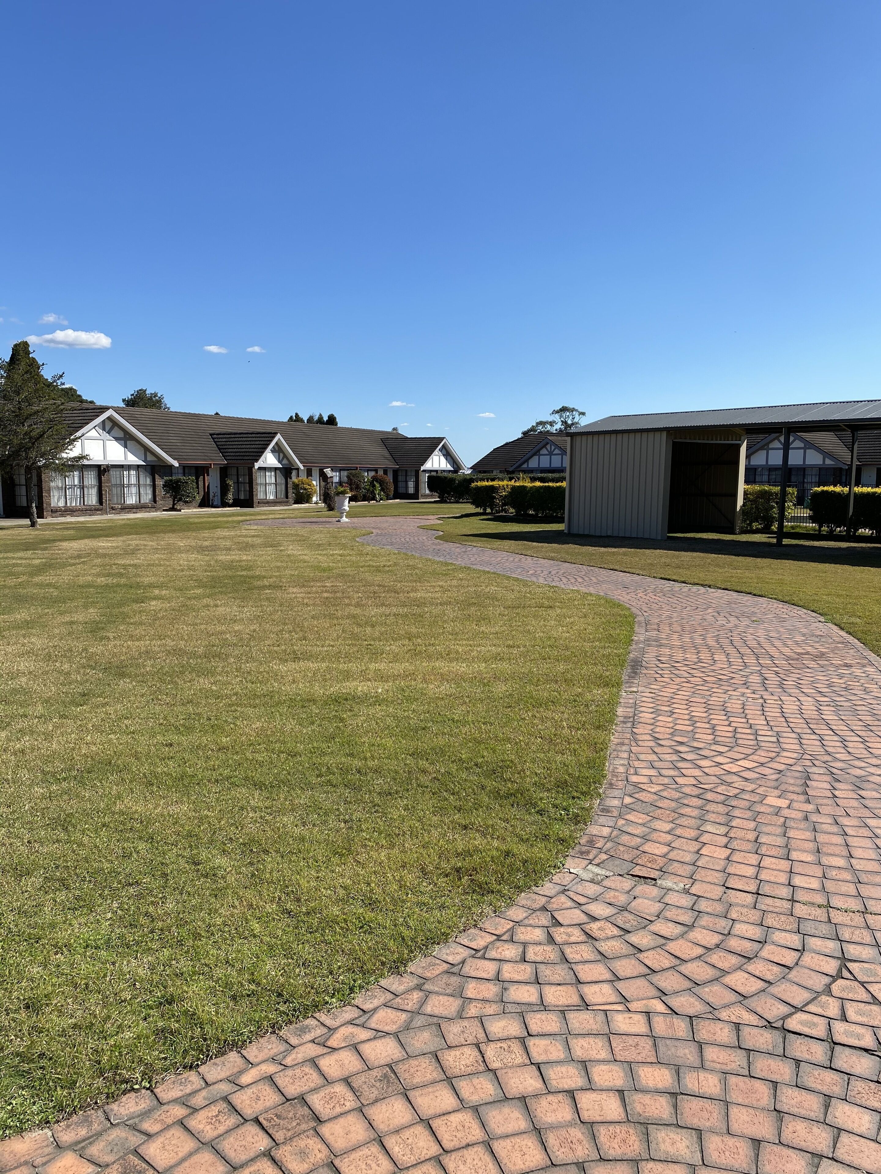 A residential area with a paved walkway, houses, and a large garage.