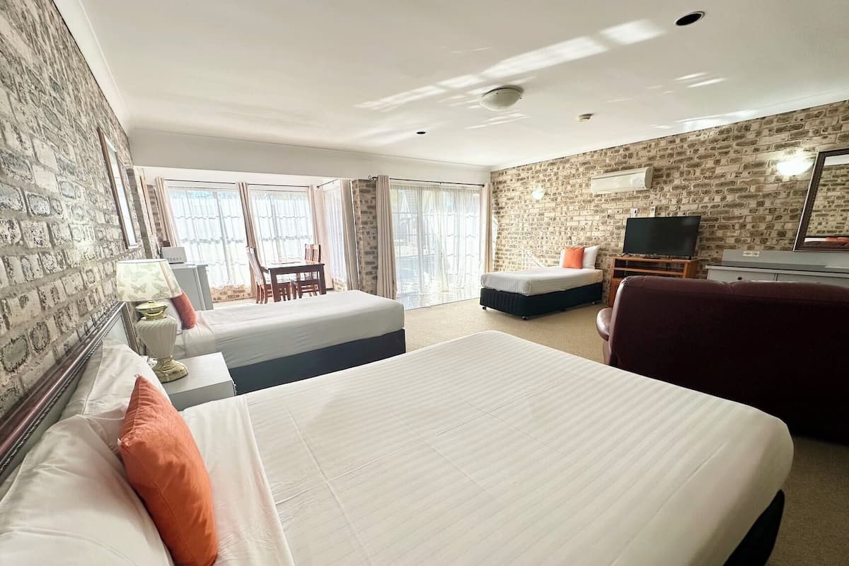 A hotel room with a large bed, a desk, a chair, a television, and a view of the outdoors.