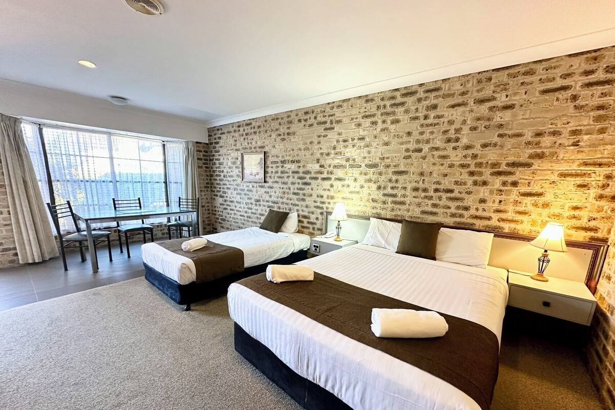 A hotel room with two beds, a desk, and a chair.