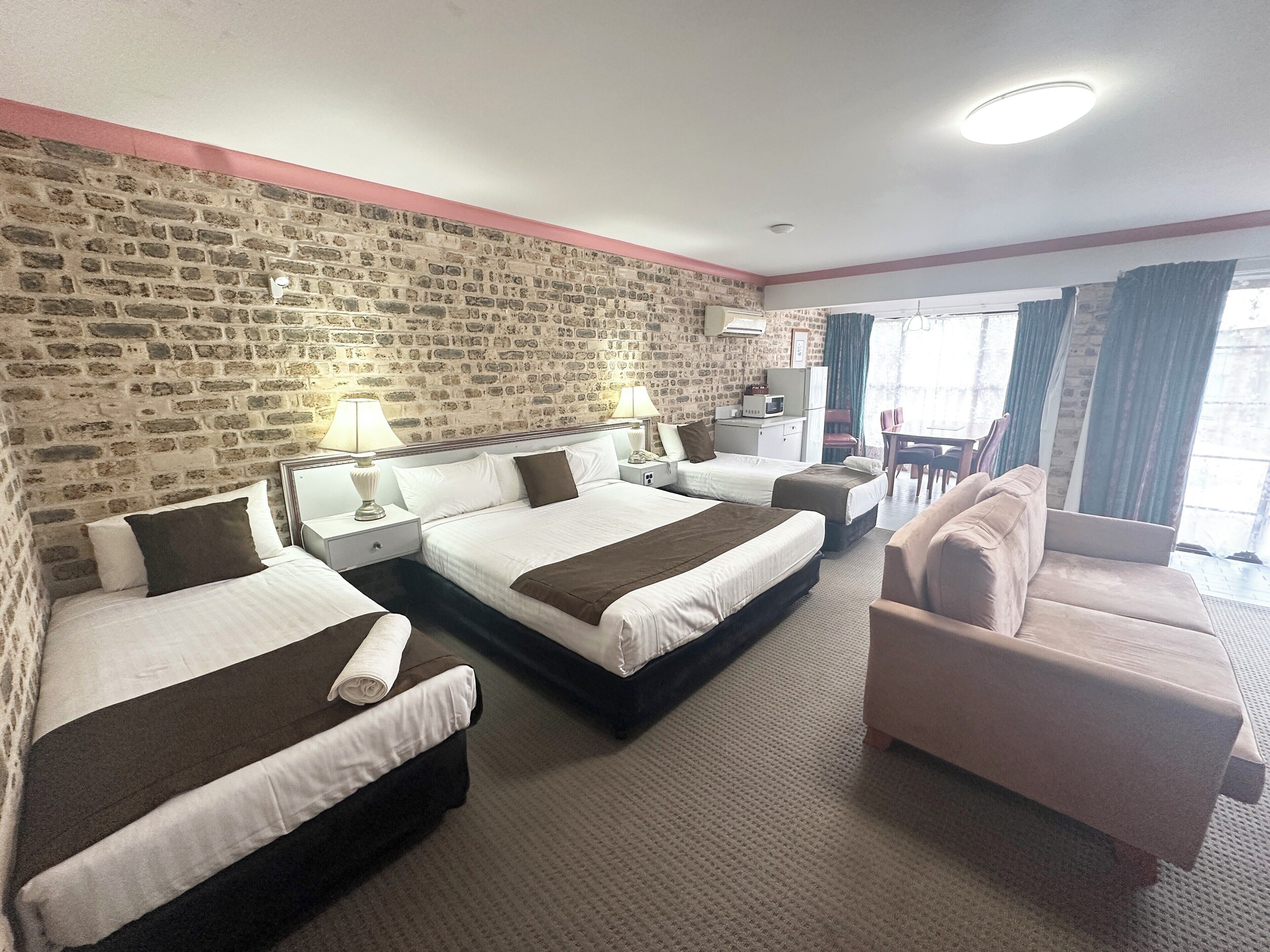 A hotel room with two beds, a sofa, a desk, and a TV.