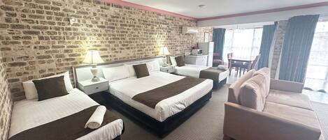 A hotel room with two beds, a sofa, a desk, and a TV.