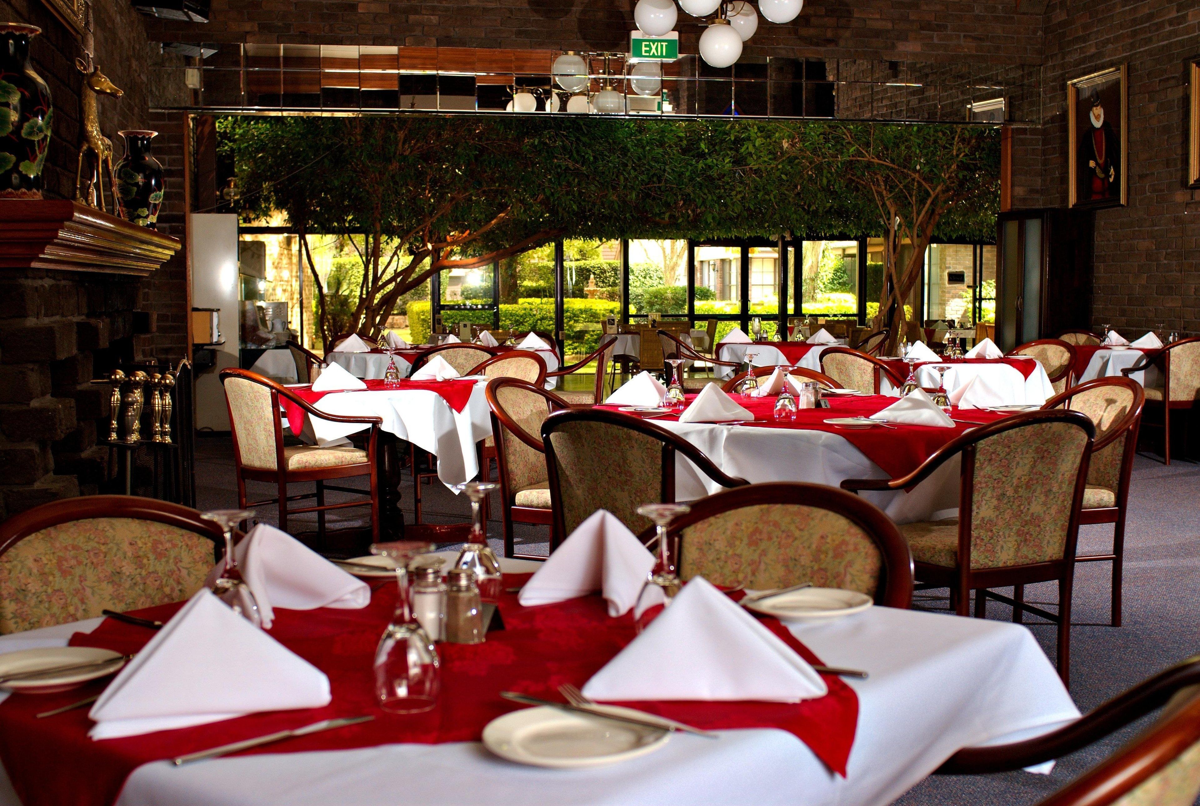 Un restaurant amb taules preparades per dinar, amb vistes a la verdura a l'exterior.