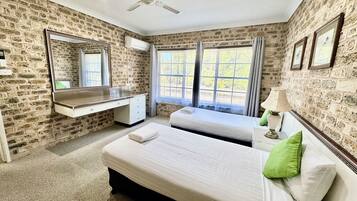 A bedroom with a large bed, a desk, a mirror, and two windows.