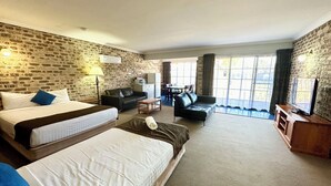 Une chambre d’hôtel avec deux lits, un canapé, une télévision et un coin repas comprenant une table et des chaises.