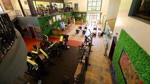 Un gimnasio con equipos de ejercicio variados, una pared verde y una escalera.