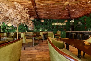 A restaurant interior with wooden flooring, green upholstered chairs, and a ceiling fan. - Colosseum Hotel & Fitness Club (Dar es Salaam)
