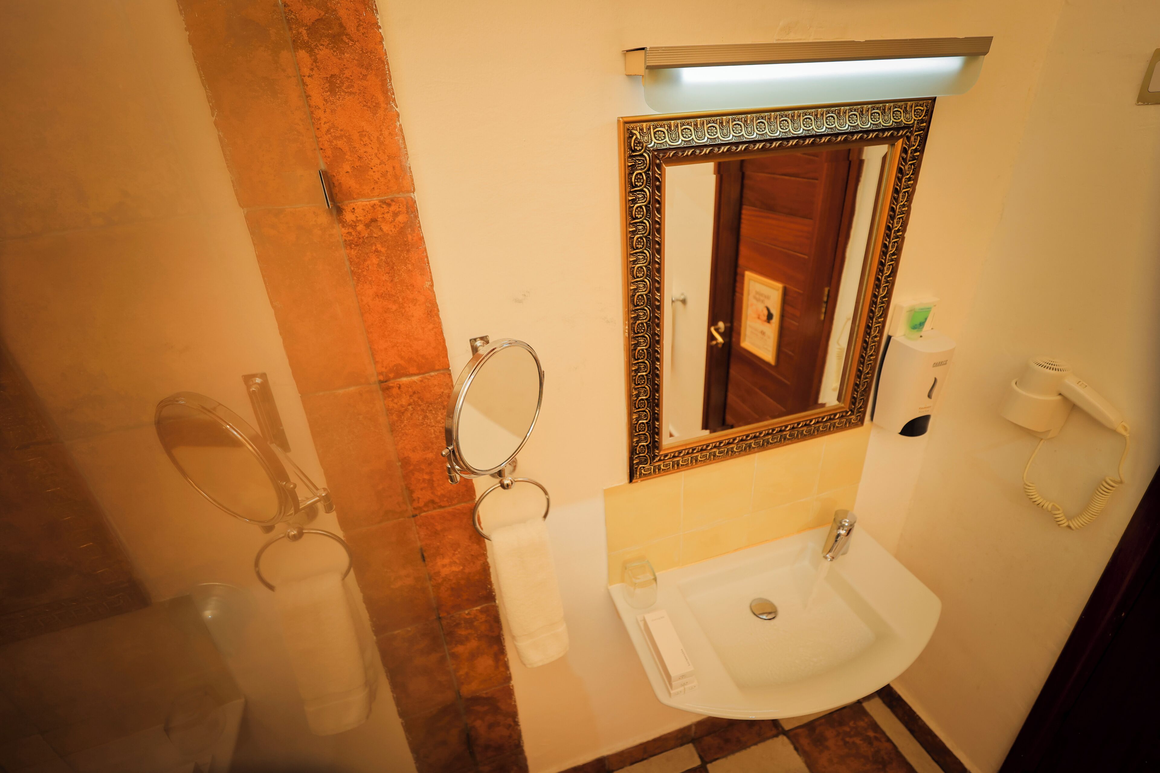 Un baño con lavamanos, espejo, toallero y retrete.
