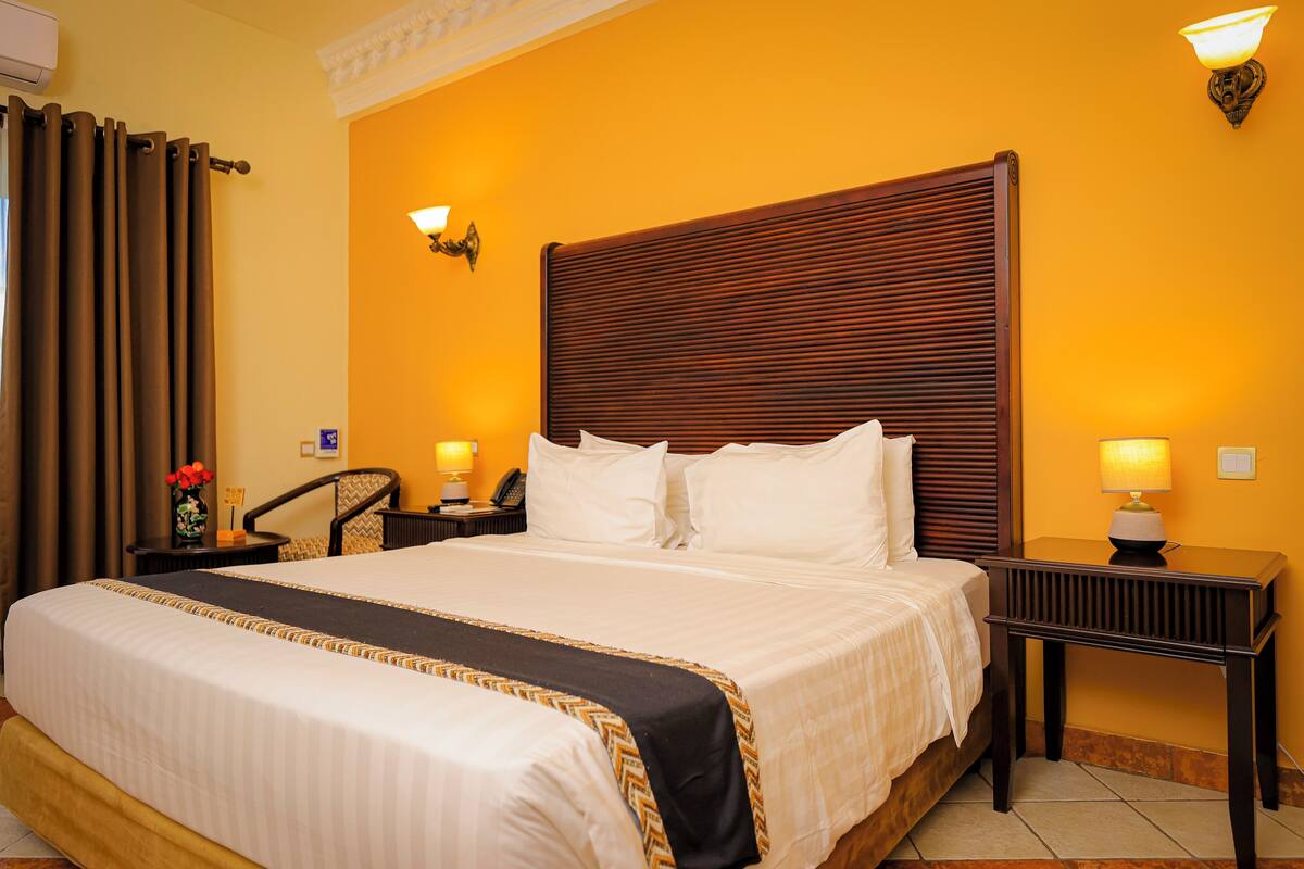 A hotel room with a large bed, two bedside tables with lamps, a chair, and a wall-mounted lamp.