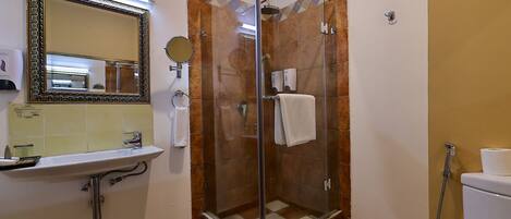 Une salle de bain avec une douche à parois de verre, un lavabo avec un miroir et des toilettes.