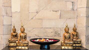 Una mesa con dos estatuas doradas de Buda y un cuenco de flores.