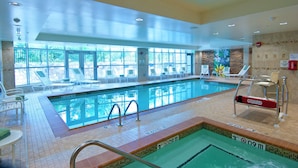 An indoor swimming pool with clear glass walls, lounge chairs, and a lifeguard chair. - Homewood Suites by Hilton Rockville-Gaithersburg (Rockville)